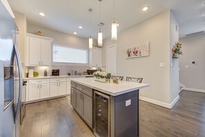 A modern kitchen with white cabinets, stainless steel appliances, and pendant lighting.