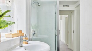 Une salle de bain moderne avec une douche à parois de verre, un lavabo blanc et un meuble-lavabo en bois.