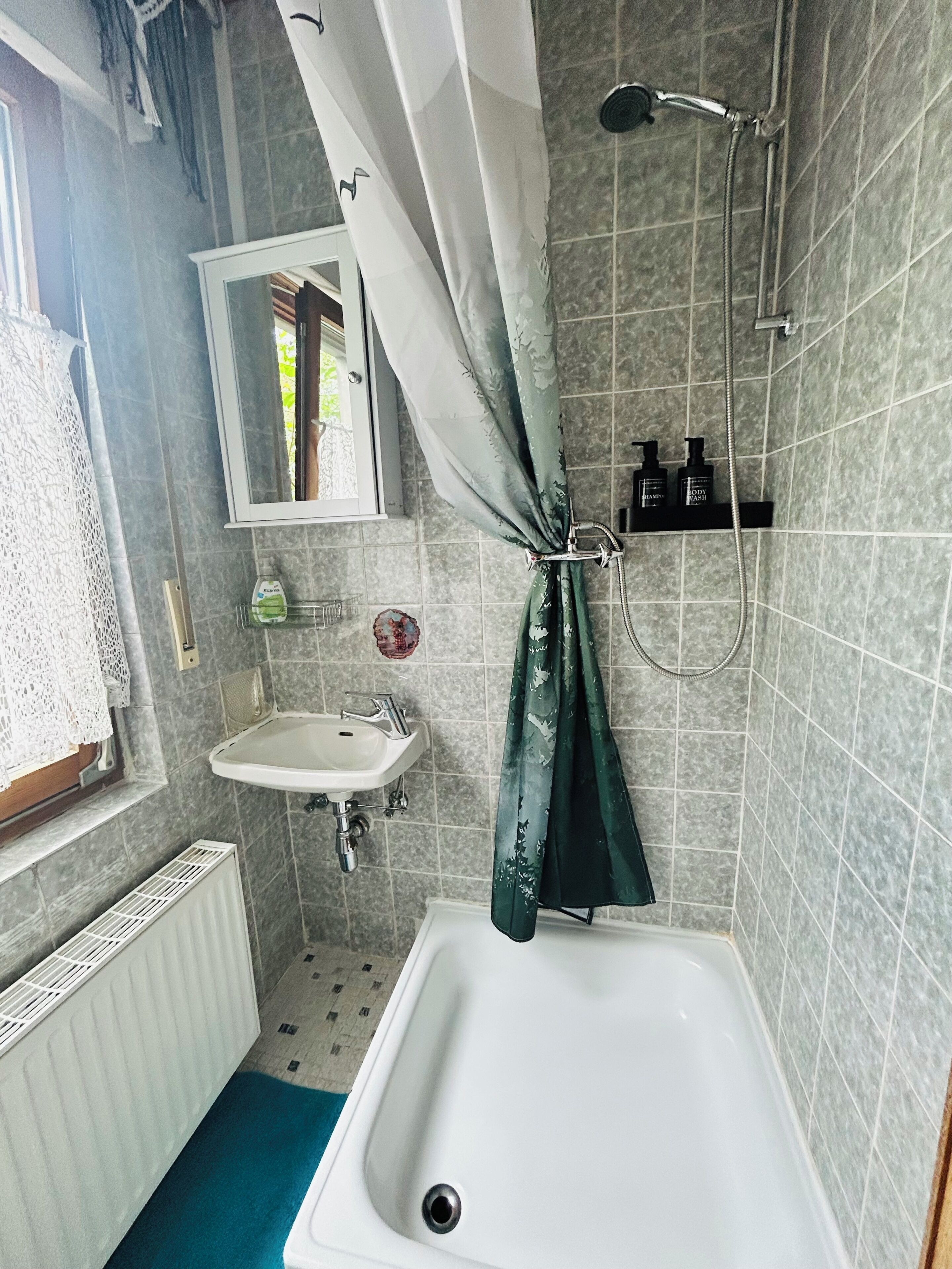 Een badkamer met een bad, een wastafel, een douche en een spiegel.