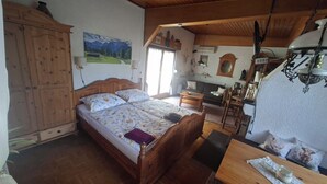 Une chambre à coucher avec un lit en bois, un bureau et un coin repas.