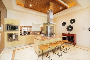 A modern kitchen with a central island, bar stools, a built-in wine cooler, and a decorative wall with circular wall art.