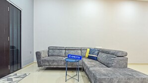 A modern living room with a grey sectional sofa, a small side table, and a blue sign reading "DZ HOMESTAY". - OYO Home 90582 Dz Homestay Bukit Ubi (Kuantan)