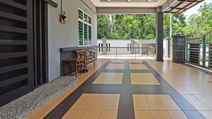 A spacious indoor area with a tiled floor, a wooden bench, and a railing overlooking a garden. - OYO Home 90582 Dz Homestay Bukit Ubi (Kuantan)