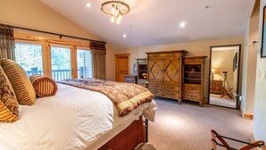 Ein Schlafzimmer mit einem großen Bett, einem Holzschrank und Blick durch ein Fenster.