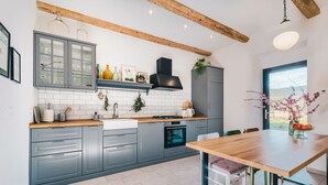 Una cucina moderna con mobili grigi, un piano di lavoro in legno e un'area pranzo con tavolo e sedie in legno.