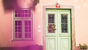 Un edificio con una porta verde e una finestra con cornice verde. Ci sono piante in vaso davanti alla porta.
