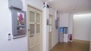 A hallway with a door, a fire extinguisher, and a water dispenser. - Hotel O iBC36 Business Stay (Kuching)