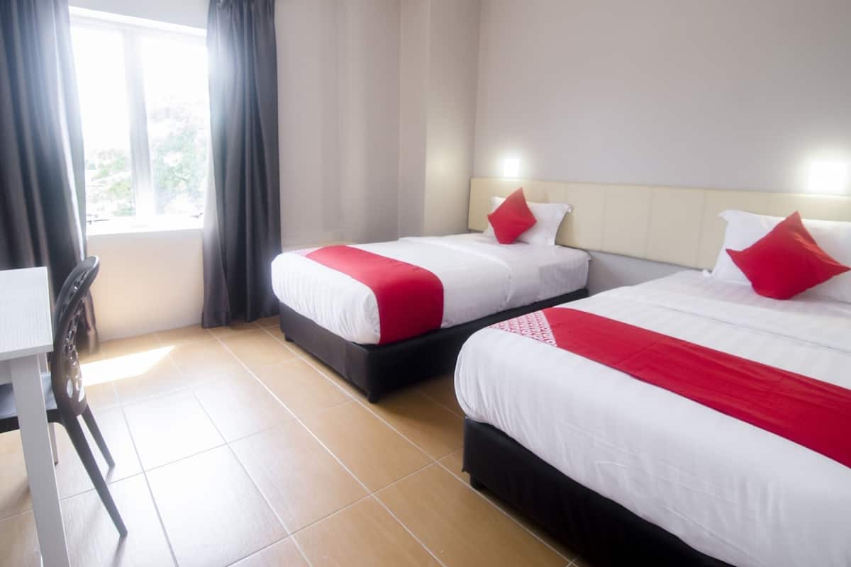 Une chambre d’hôtel avec deux lits, un bureau et une fenêtre avec des rideaux.
