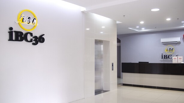 A modern reception area with a clean, minimalist design, featuring a reception desk, a wall-mounted air conditioning unit, and a digital display. - Hotel O iBC36 Business Stay (Kuching)