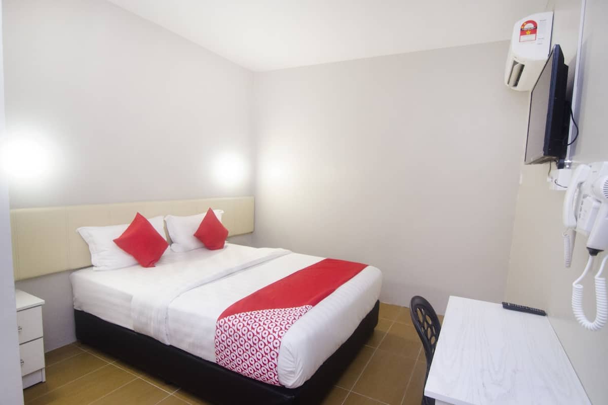 Une chambre d’hôtel équipée d’un lit, d’un bureau, d’une chaise, d’un téléphone et d’un appareil fixé au mur.