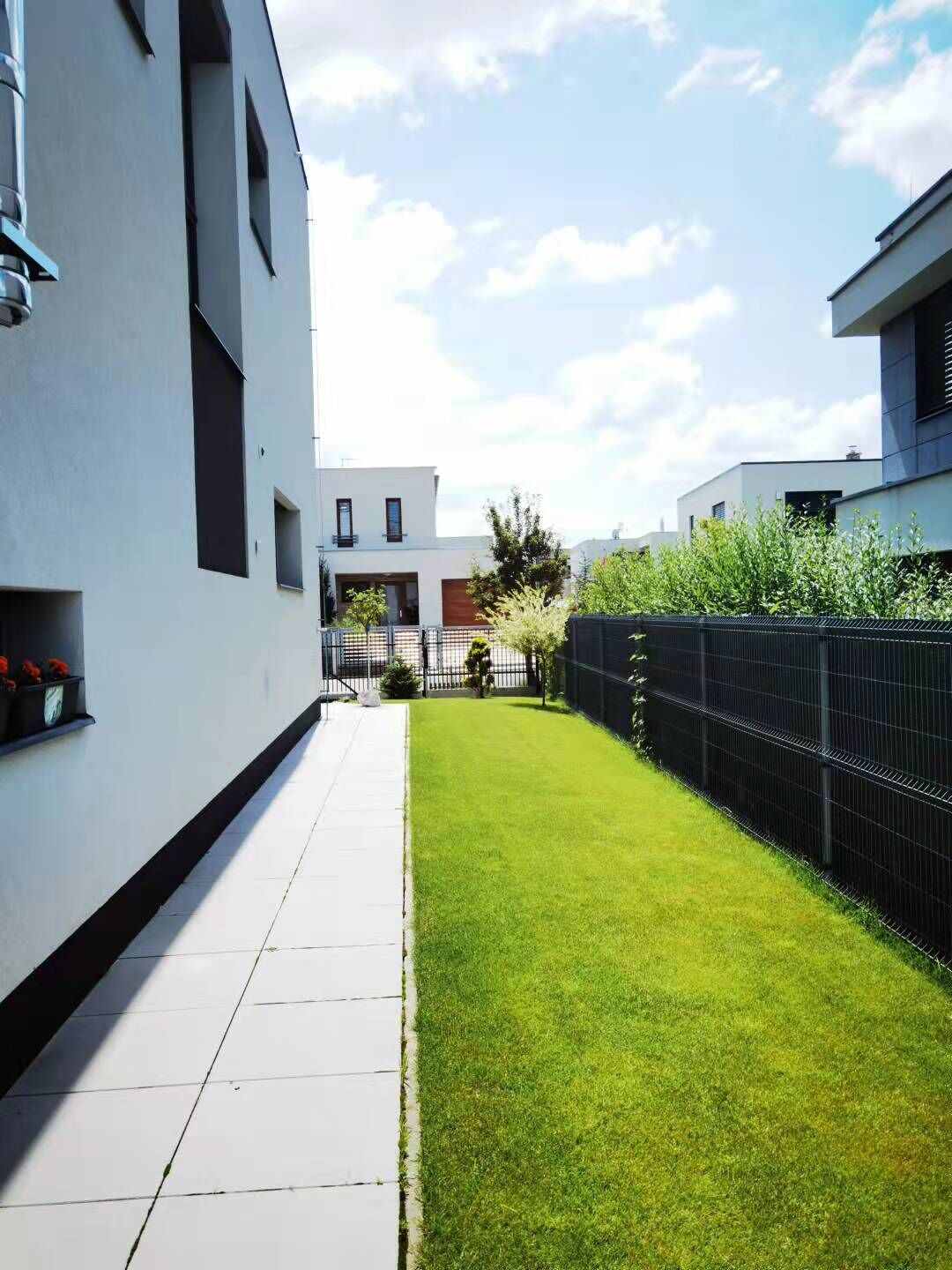 En modern bostadsbyggnad med en välskött gräsmatta och ett staket av metall.