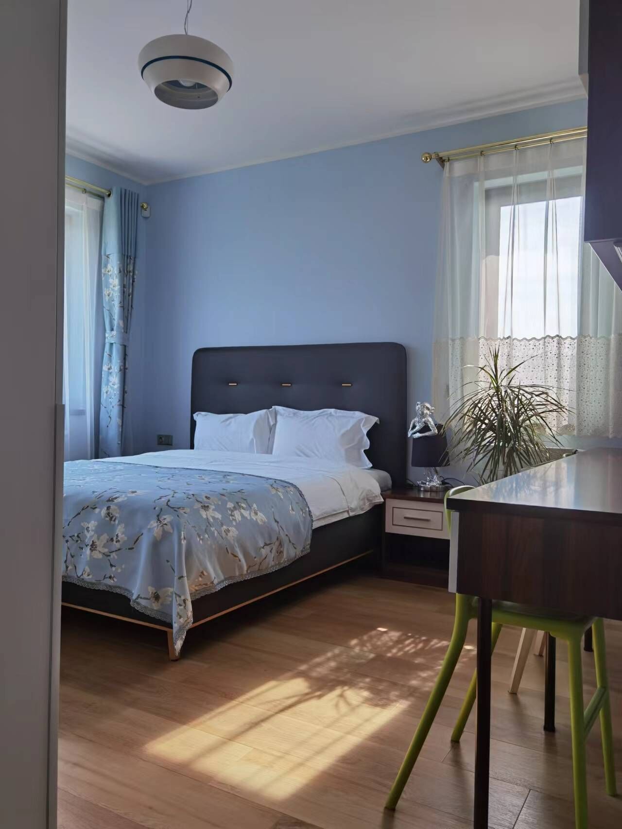 Een slaapkamer met een bed, nachtkastje, lamp en stoel.
