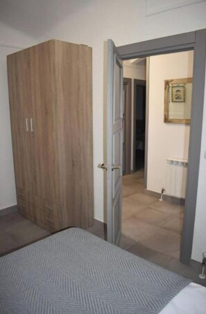 A bedroom with a bed, a wardrobe, and a door leading to a bathroom.