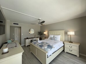 A bedroom with a bed, bedside tables, a dresser, a ceiling fan, a mirror, and a nightstand with lamps. - DIRECT BEACHFRONT Views from the 15TH FLOOR! Listen to Ocean Waves! WOW! (Jensen Beach)