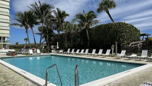 Una piscina con sillones de descanso y palmeras.