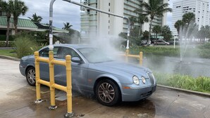 Un coche aparcado cerca de una fuente con una barrera amarilla.