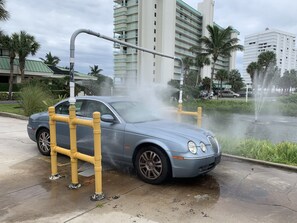 Carro estacionado perto de um espelho d'água com uma barreira amarela.