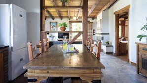 A rustic kitchen with a wooden table, chairs, a refrigerator, and potted plants. - Home2Book Atlantic View Rustic Villa (Los Realejos)