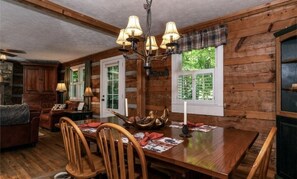 Un intérieur en bois comprenant une table à manger, des chaises, un lustre et une cheminée.