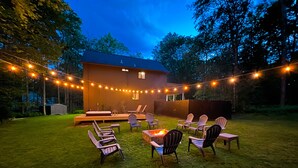 A backyard with a fire pit, outdoor seating, and string lights. - Poconos Hideaway Hot Tub, Zen Garden & Fire Pit, hiking and water parks nearby. (Albrightsville)