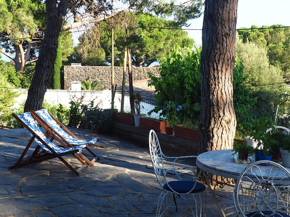 A patio with a stone floor, a metal table, and two chairs.