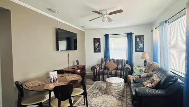 A living room with a dining area, a ceiling fan, a flat-screen TV, and a sofa with patterned cushions. - Two bedrooms cute and cozy house in Melbourne (Melbourne)