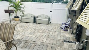 A patio with a herringbone tile pattern, outdoor furniture, a potted plant, and a white fence. - Two bedrooms cute and cozy house in Melbourne (Melbourne)