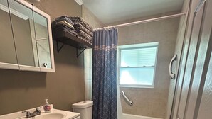 A bathroom with a white sink, toilet, and bathtub. There is a window with blinds, a mirror, and a towel rack with towels. - Two bedrooms cute and cozy house in Melbourne (Melbourne)