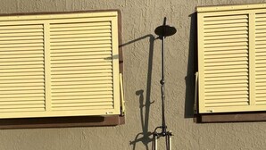 A garden hose mounted on a wall with a metal pole, a window with yellow shutters, and a stone border. - Two bedrooms cute and cozy house in Melbourne (Melbourne)
