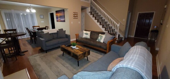 A living room with a sofa, coffee table, and a staircase leading to the upper floor.
