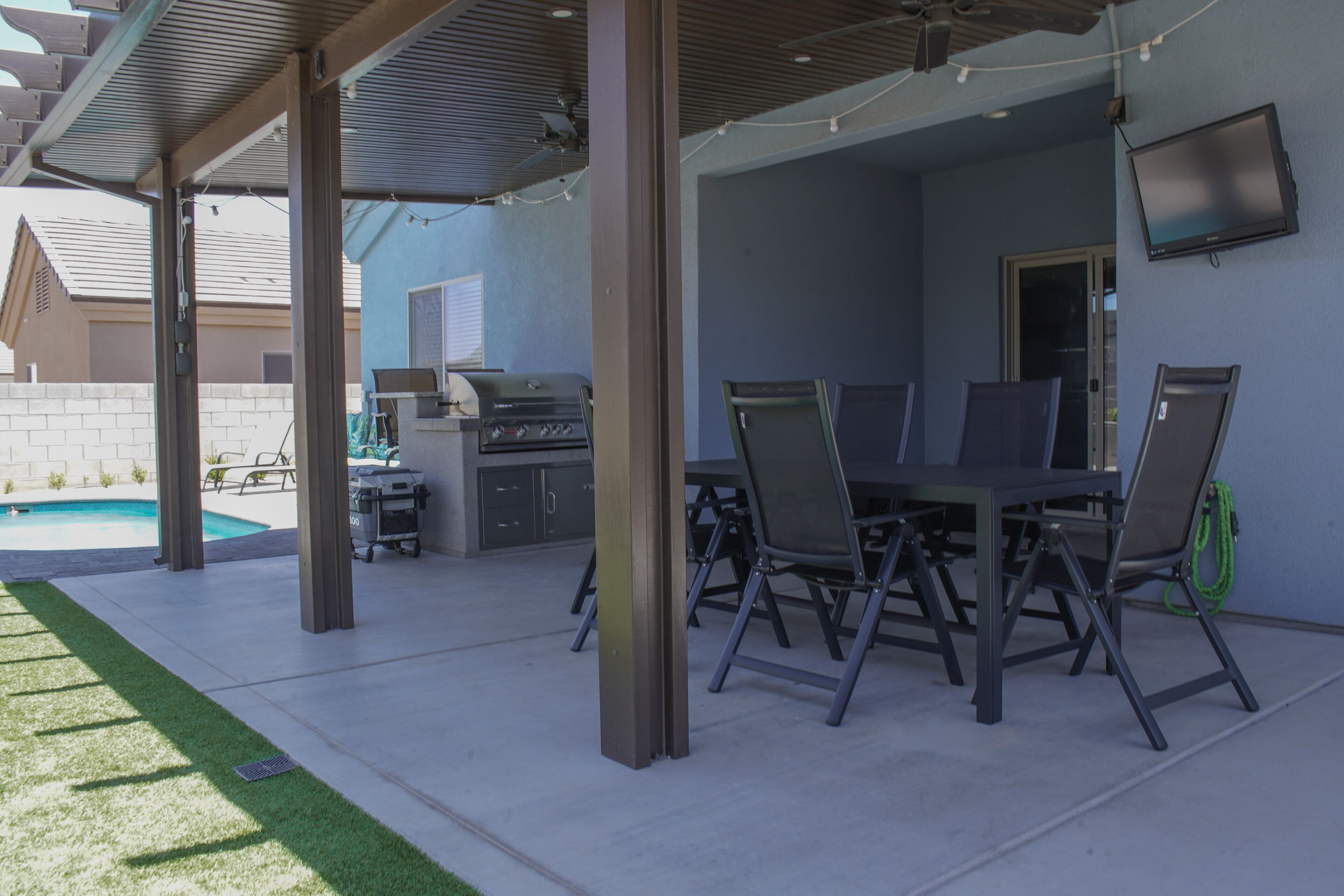 An outdoor patio with a grill, dining table, and chairs.