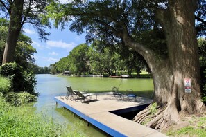 A dock extending into a calm river, surrounded by lush greenery and trees.