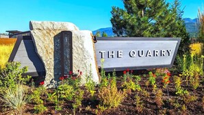 A sign reading 'THE QUARRY' with a stone structure and a wooden deck in front. - EV Charger | Amazing Views | Pool & Hot Tub (Whitefish)