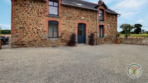 A stone building with a gravel driveway, two doors, and a small porch area. - La Maison aux Portes des Ecluses (HEDE BAZOUGES)