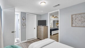 Une chambre à coucher avec un lit, une commode, une télévision et un placard.