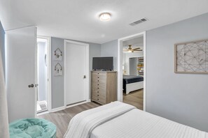 A bedroom with a bed, a dresser, a TV, and a closet.