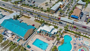 Vue aérienne d’un complexe hôtelier doté de plusieurs piscines, d’une plage et d’un parking.