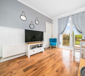 Relax in this stylish living room with a large flat-screen TV, comfortable seating, and a dining area.