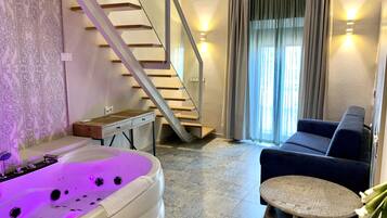 Una sala de estar moderna con un jacuzzi, una escalera, un sofá y una pequeña mesa redonda.