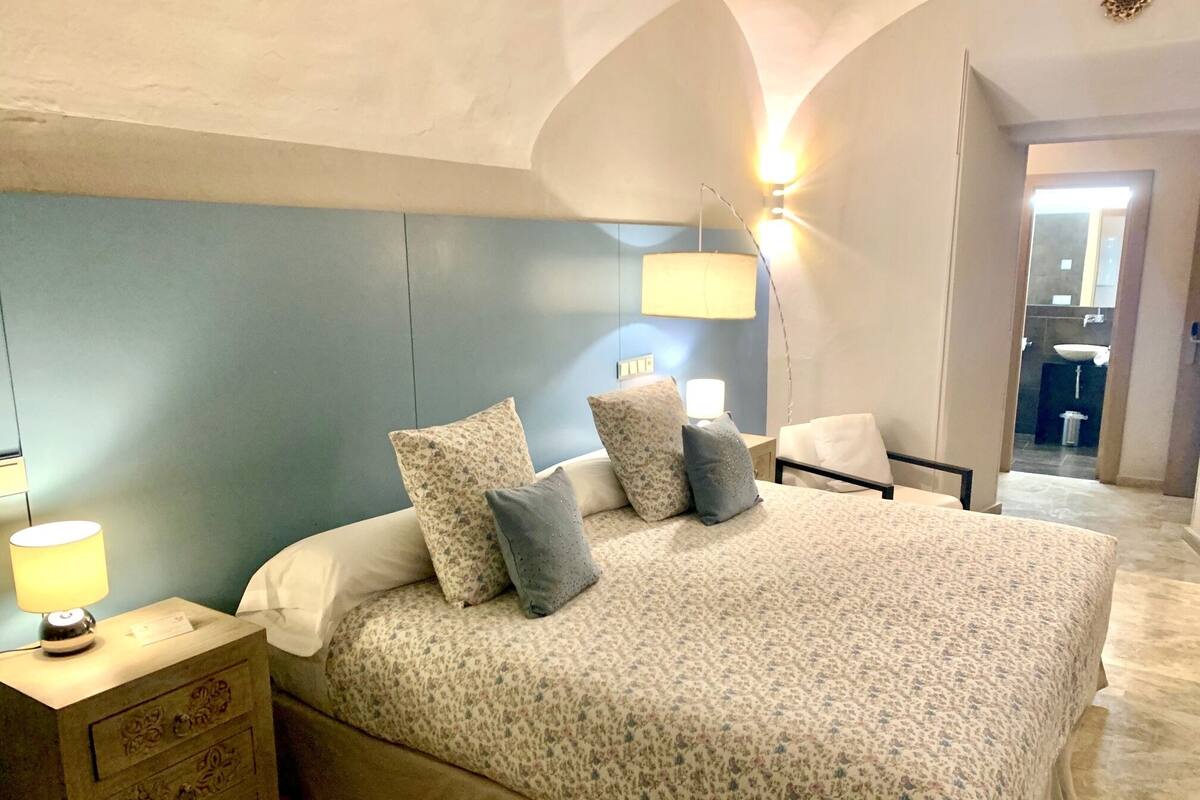 A bedroom with a bed, nightstands, and a lamp.