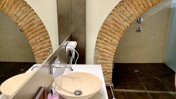 A bathroom with a large mirror, a round sink, a hairdryer, and a towel rack.