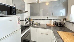 Een compacte keuken met een magnetron, broodrooster, spoelbak en kastjes.