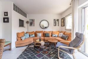 Un salon avec un canapé d’angle, un miroir rond et un tapis à motifs.