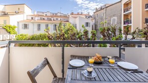 Een balkon met een ontbijttafel, inclusief croissants, sinaasappelsap en koffie.