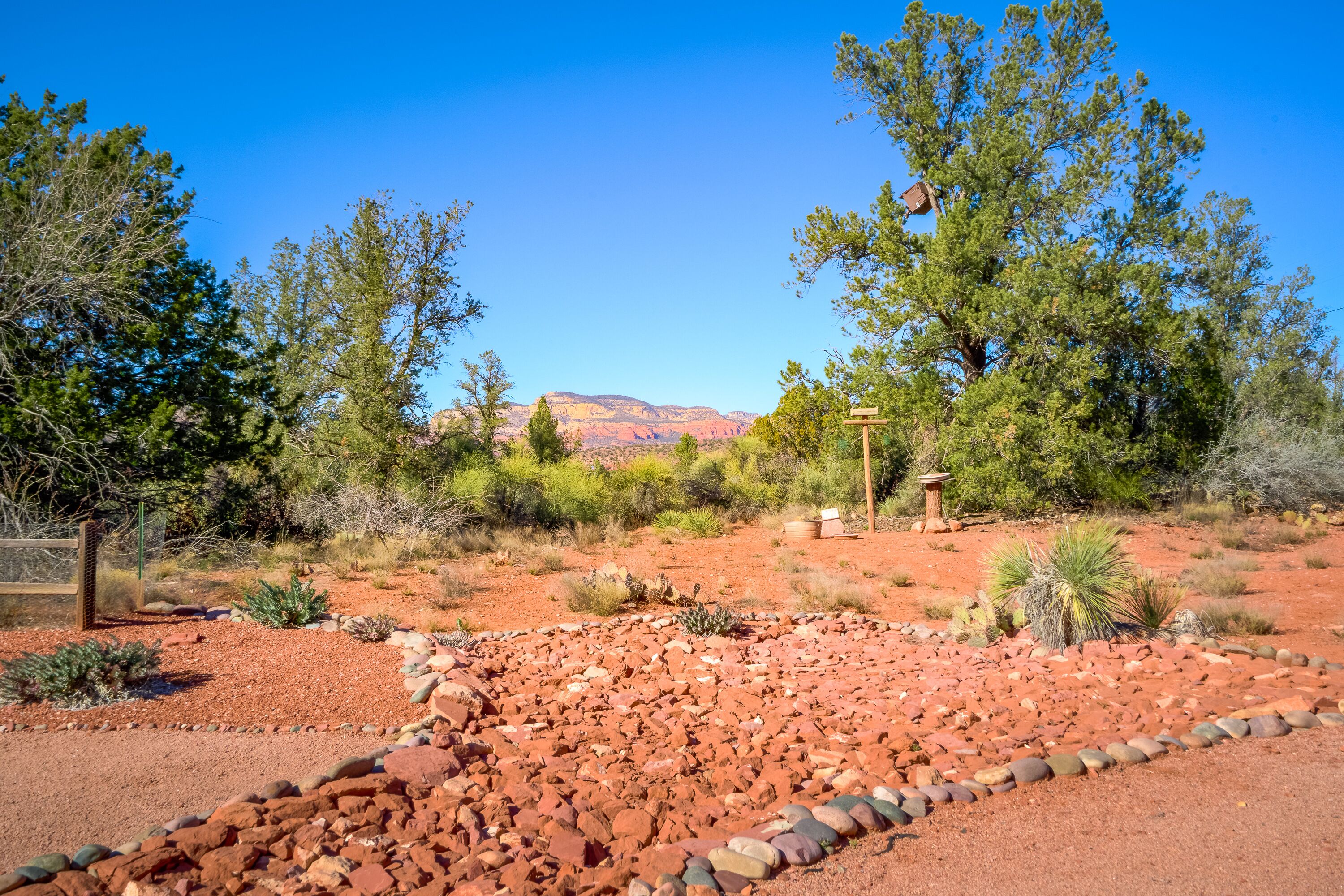 A desert landscape with red rocks, sparse vegetation, and a clear blue sky.