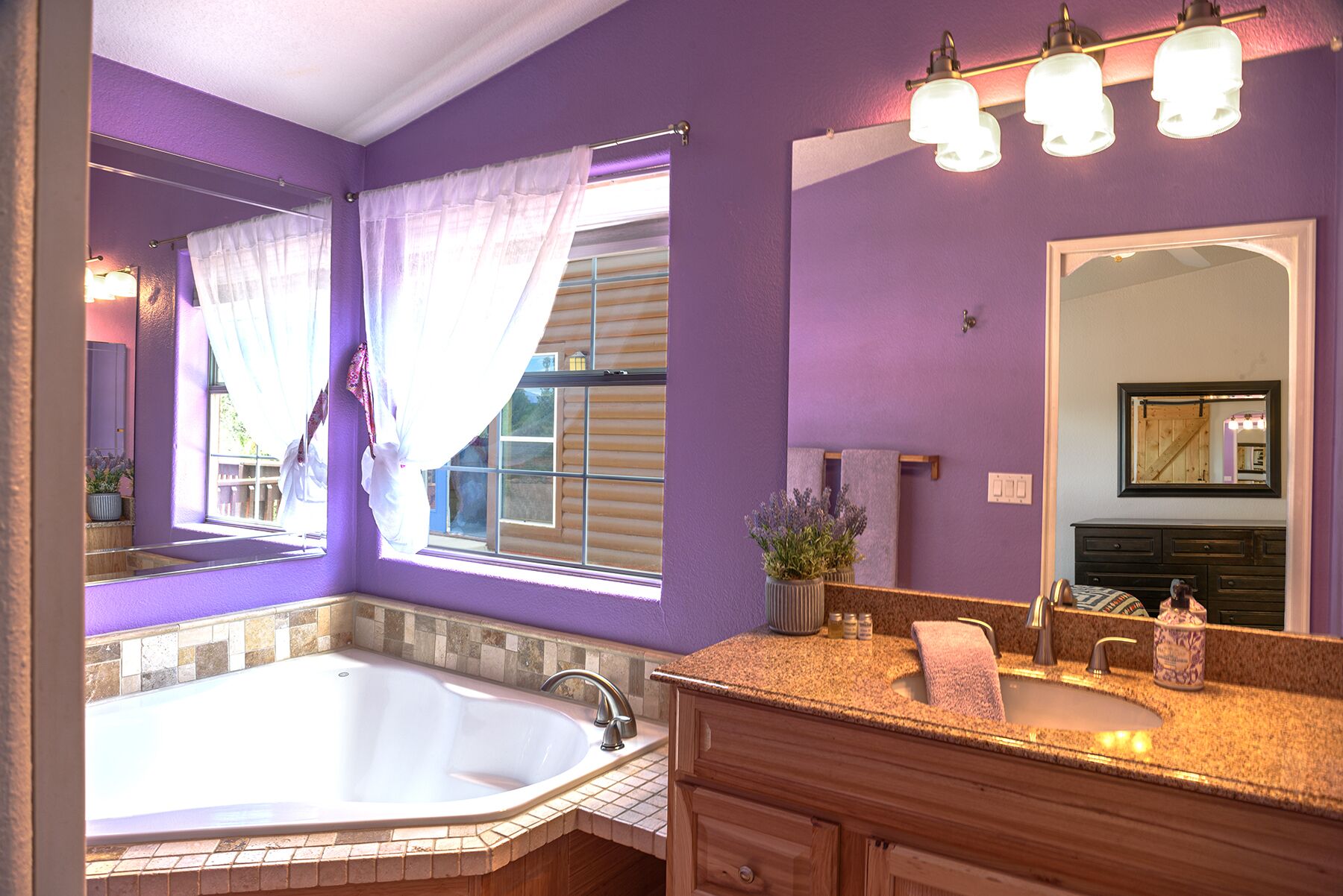 A bathroom with a large bathtub, a vanity with a sink, and a mirror.