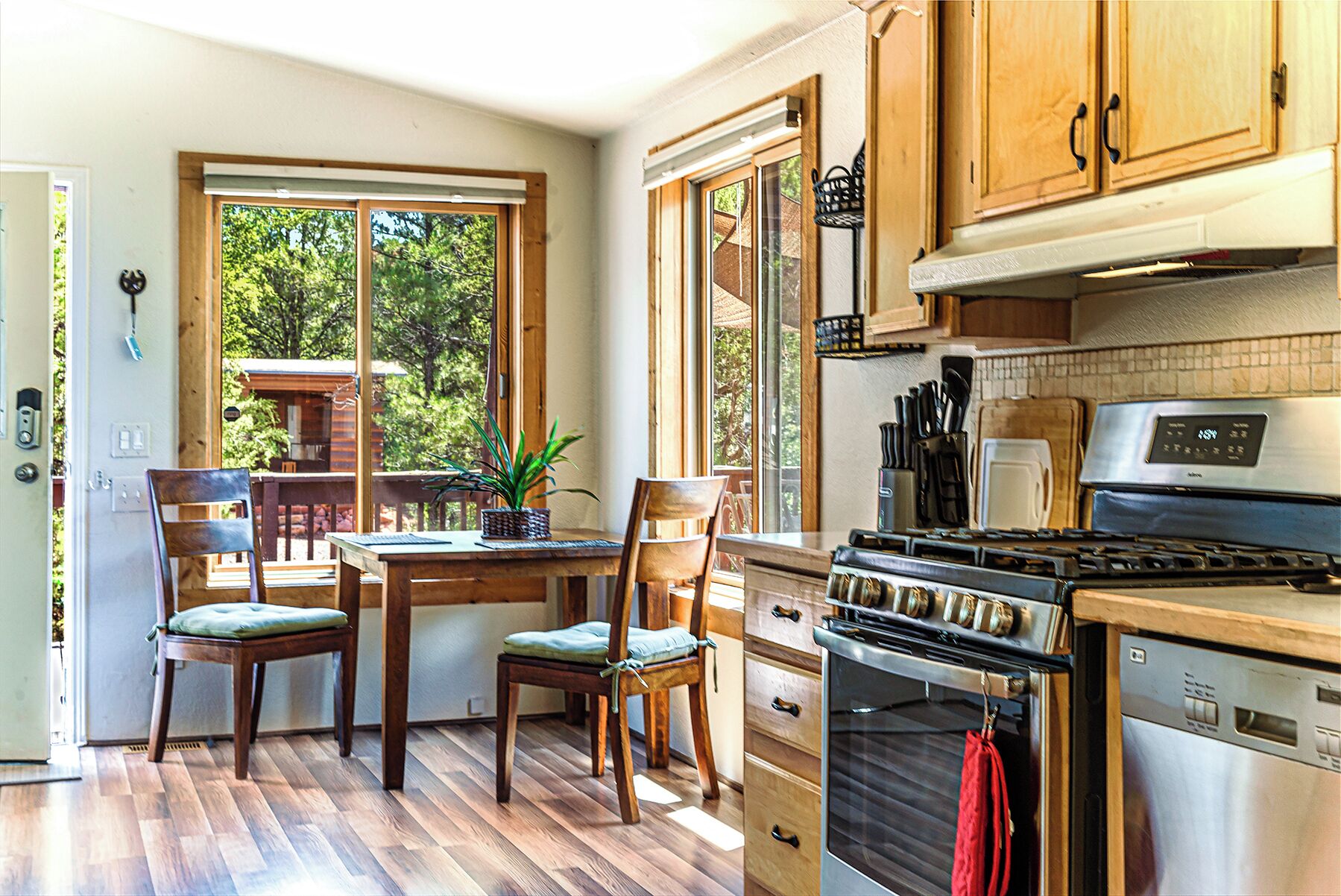 Une cuisine avec des meubles en bois, une cuisinière et un coin repas comprenant des chaises et une table.