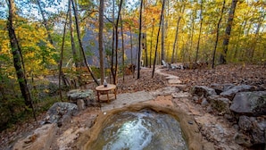 A hot spring surrounded by rocks and trees in a forest.