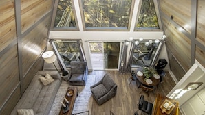 A spacious loft with a high ceiling, large windows, a staircase, and a cozy seating area with a fireplace.