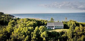 A house surrounded by dense forest with a view of the ocean.